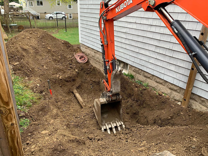 Excavator digging beside house