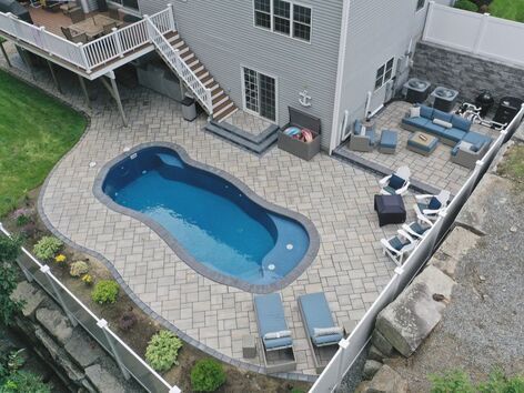 In ground pool installation with paver pool surround and outdoor patio for seating